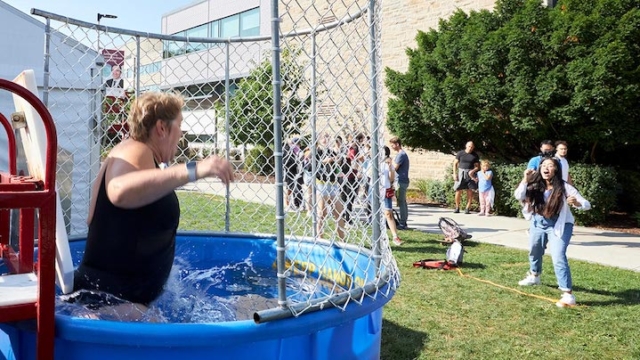 Heather Sheardown goes down into the dunk tank as the successful student thrower cheers in the background