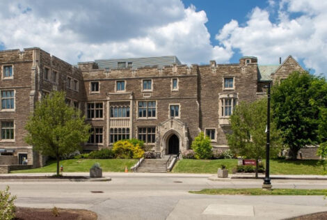 Hamilton Hall with a blue cloud filled sky and green trees around it