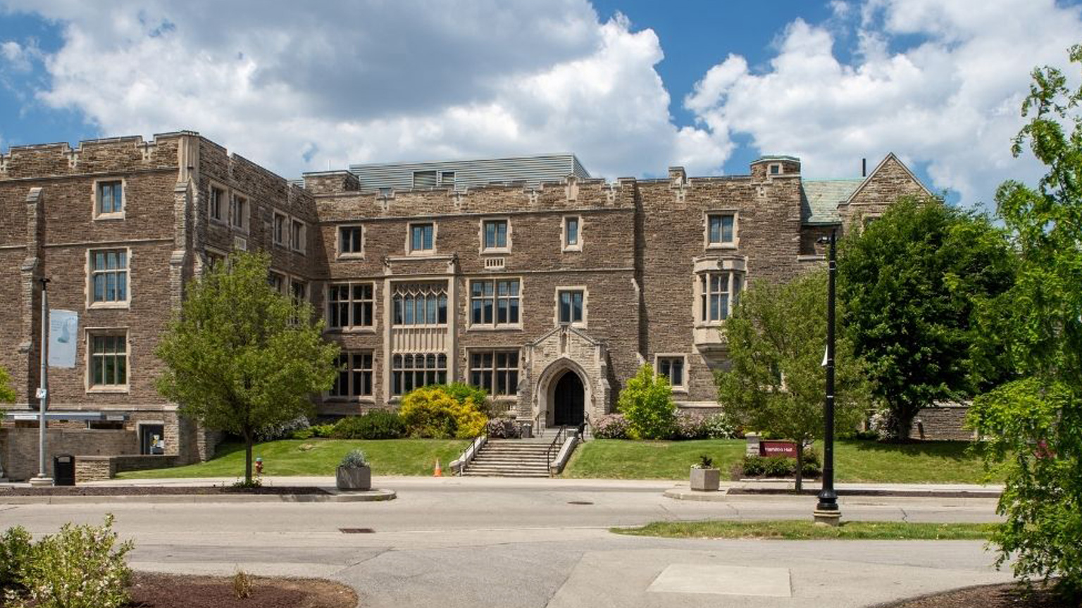 Hamilton Hall with a blue cloud filled sky and green trees around it