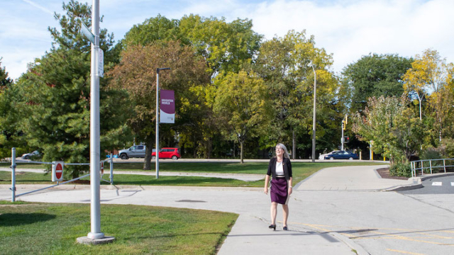Donna Strickland walking to a street sign that has her last name on it.