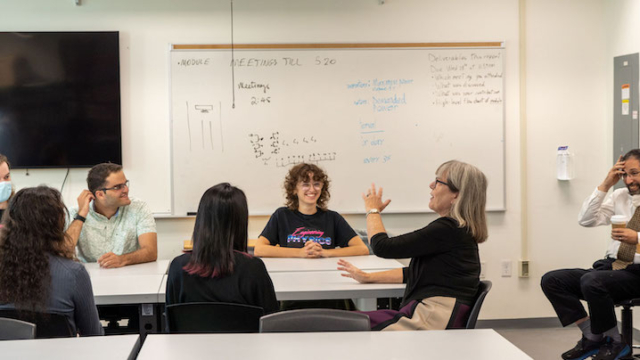 Donna Strickland speaking to students in a classroom, a student beside her is smiling