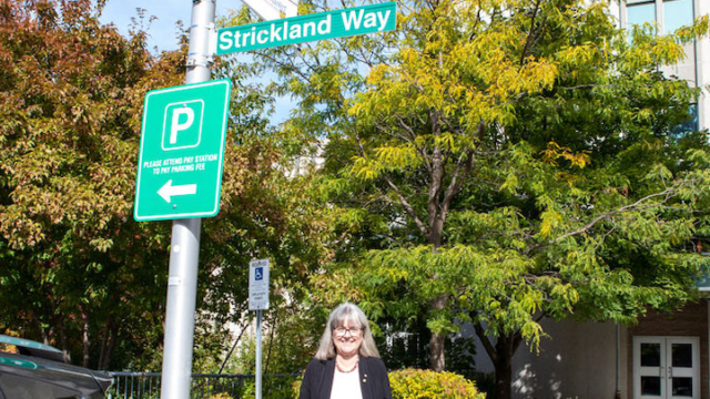 Donna Strickland standing beside new street sign that has her last name on it.