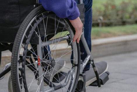 A hand rests on the wheel of a wheelchair.