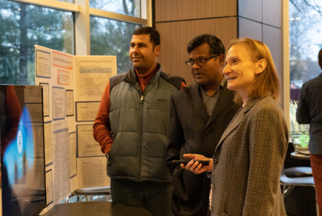 Three people attending the Research Fair checking out a research poster