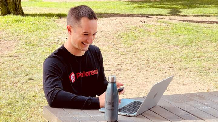 man sitting at a picnic bench looking at his laptop.