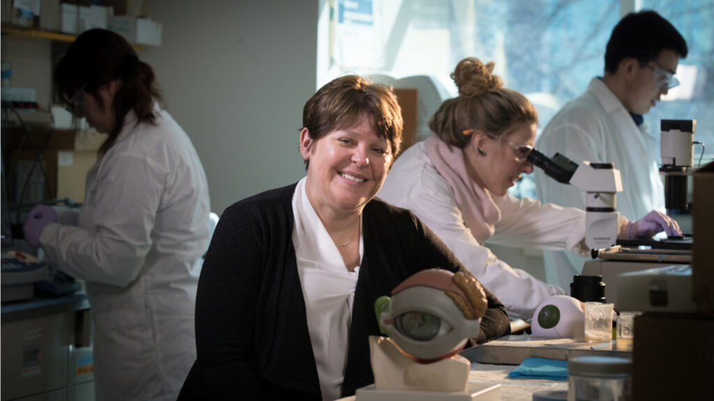 Heather Sheardown sits in a lab with a model eye