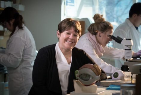 Heather Sheardown sits in a lab with a model eye
