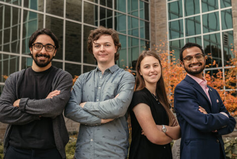 four people standing in front of a building with their arms crossed in front of them.