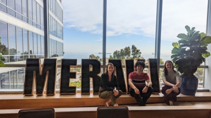 three people sitting in front of a sign. 