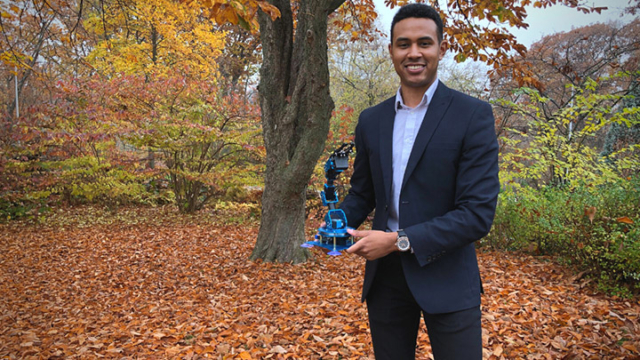 Michael Jobity holds up device in front of a tree outdoors.