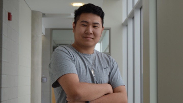 headshot of person in hallway with their arms crossed.