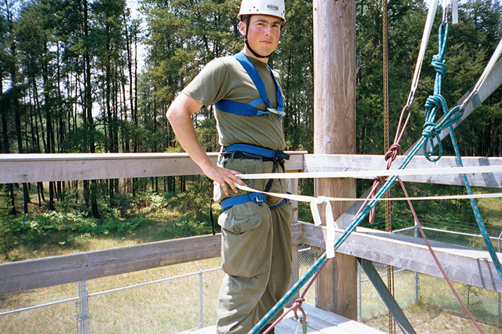 Omar Danta stands in a helmet and harness on a wooden platform.