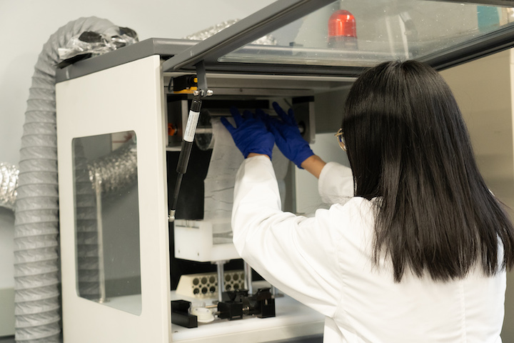 Wu loading paper substrate onto the electro spinner (instrument used to produce nanofibers for filter material).