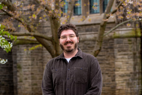 James Lemoine poses by spring trees on campus