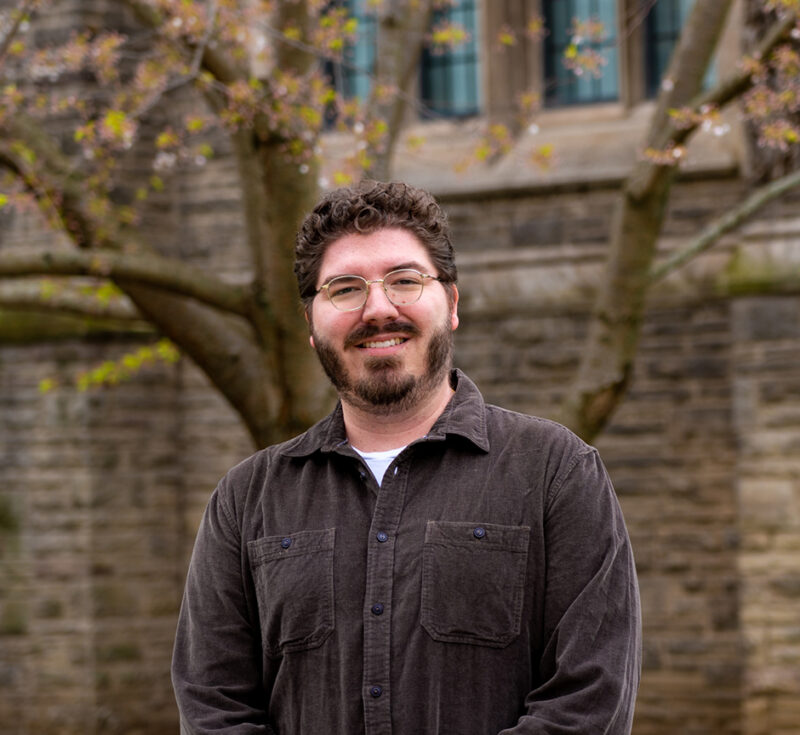 James Lemoine poses by spring trees on campus