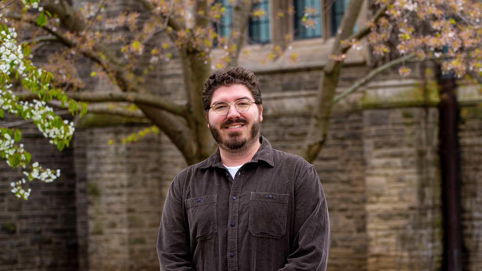 James Lemoine poses by spring trees on campus