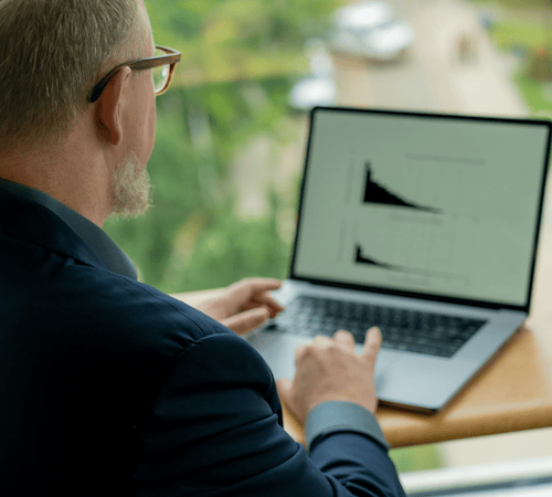 blurry computer screen showing graphs seen over man's shoulder.