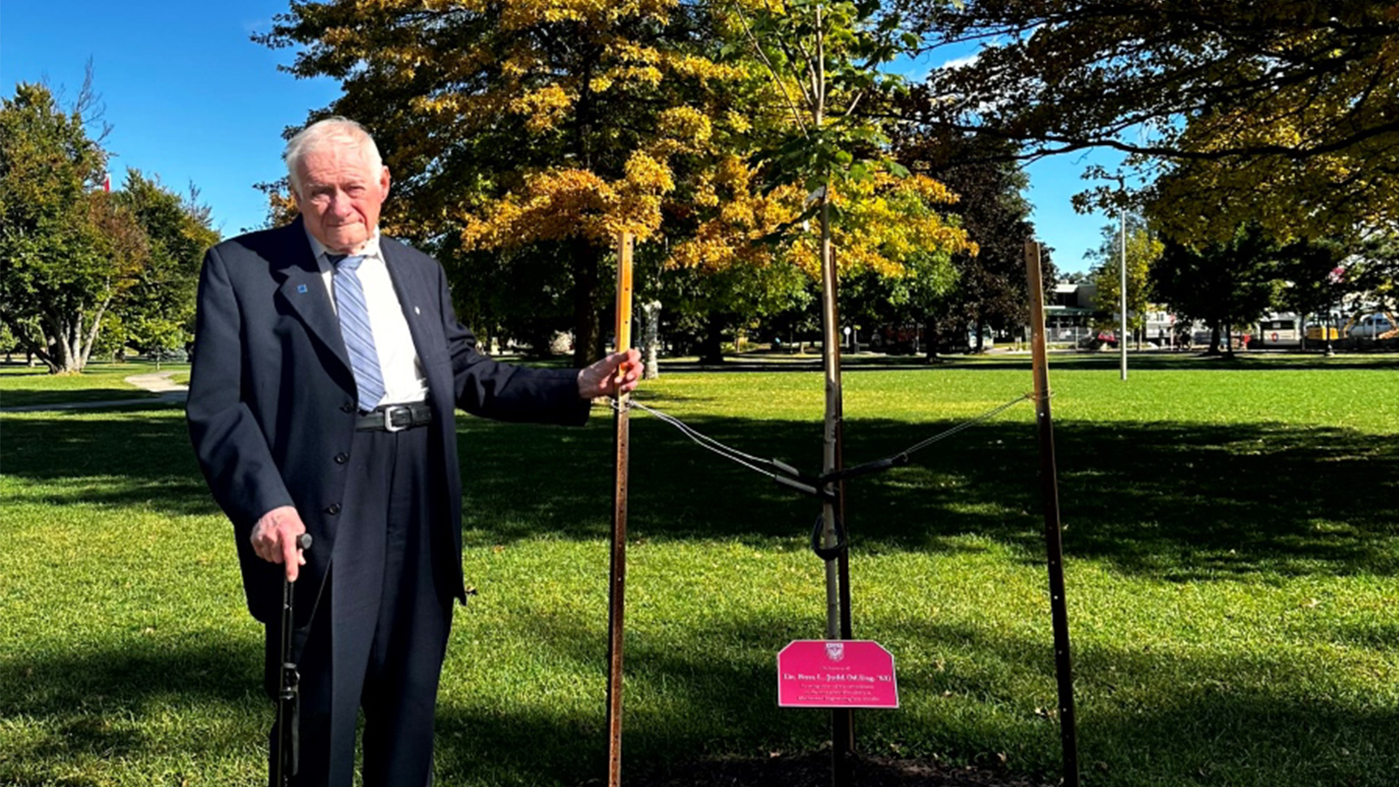Ross Judd stands beside the tree that was planted on the JHE lawn in his honour