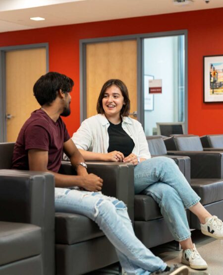 Two students sitting and chatting in the academic advising waiting room