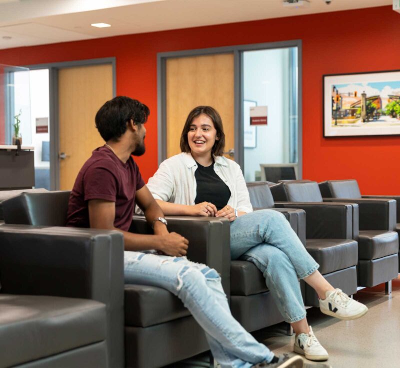 Two students sitting and chatting in the academic advising waiting room