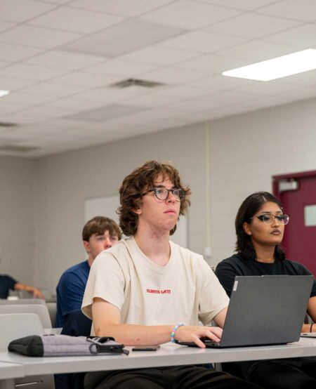 Student looking up from laptop in EMBER Mock Lab