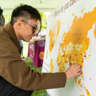 Student putting a pin into a world map at Mac Eng Reignites.