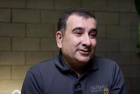 Ali Emadi sits in front of a brick wall that is backlit.