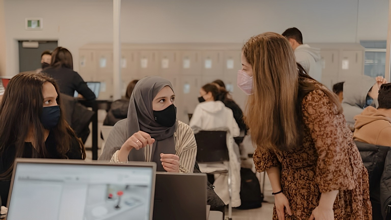 Two students speak with a TA in their 1P13 class