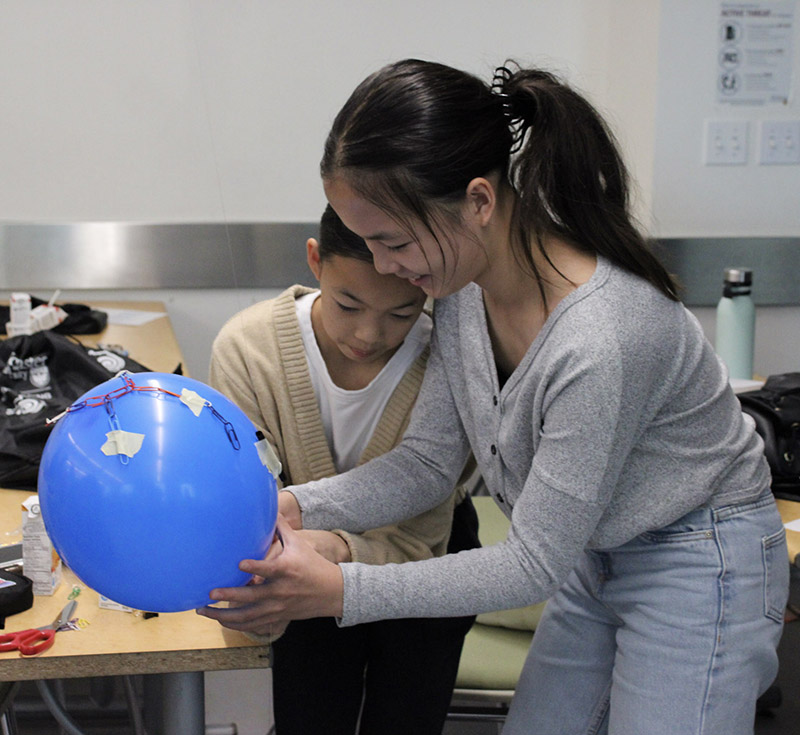 Two girls working on a balloon experiment together