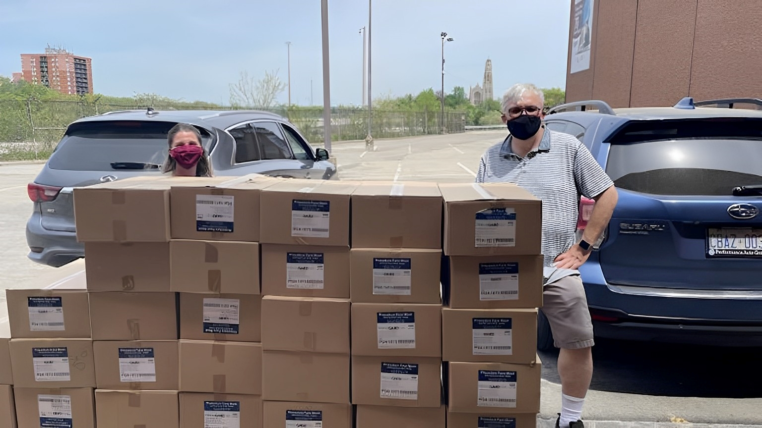 two people standing behind a large stack of boxes.