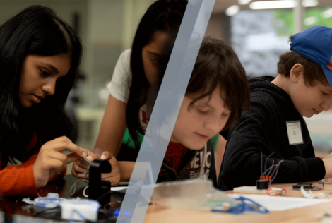 school aged children sitting at a table working on engineering projects.