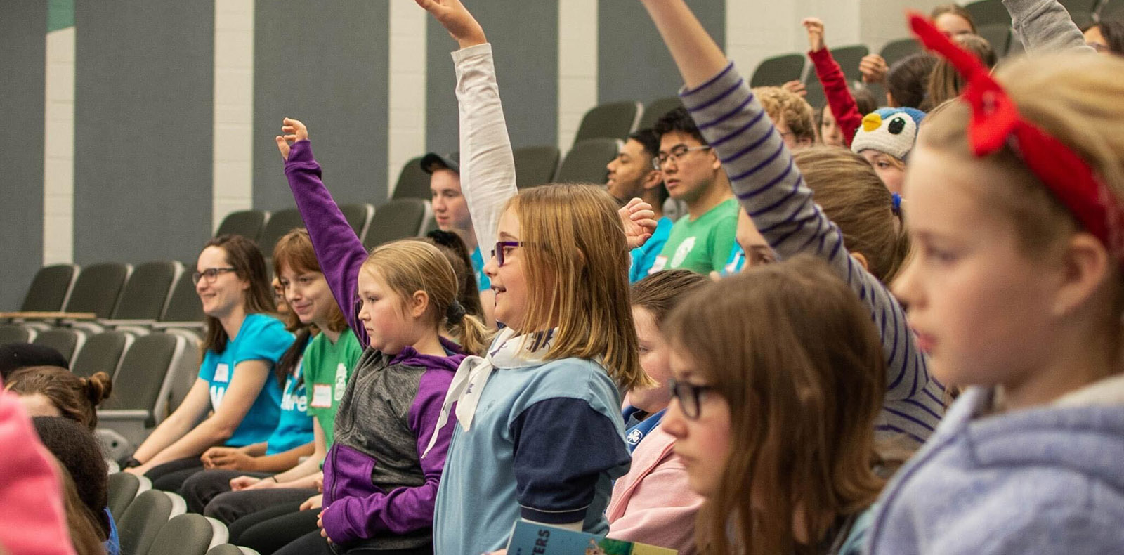 Kids in a classroom raising hands