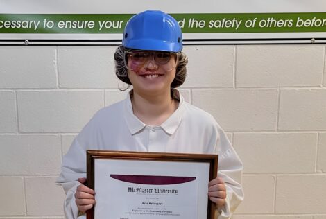 person at work wearing a hard hat and holding up a framed certificate.