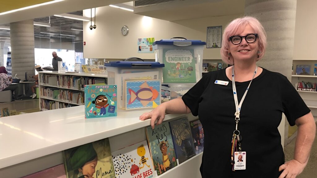 woman standing in front of shelf of books at the library.