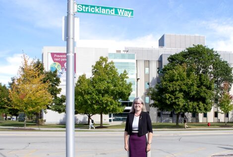 Donna Strickland standing in front of a street sign that reads Strickland Way.