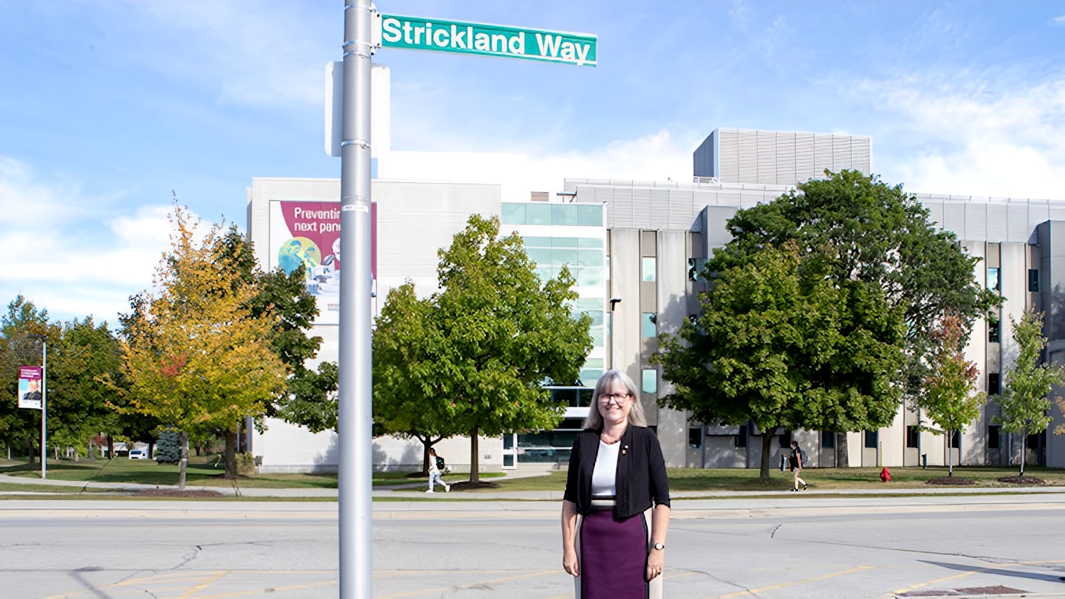 Donna Strickland standing in front of a street sign that reads Strickland Way.