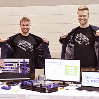 Two students displaying their project and t-shirt with matching logos