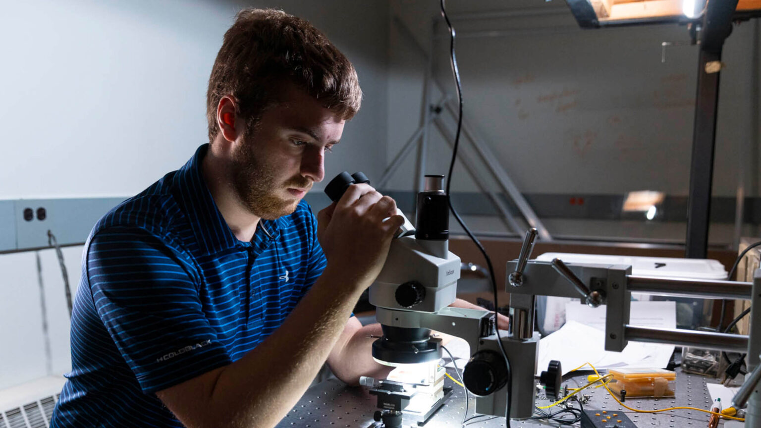 A person looks into a microscope in the Engineering Physics optics lab.