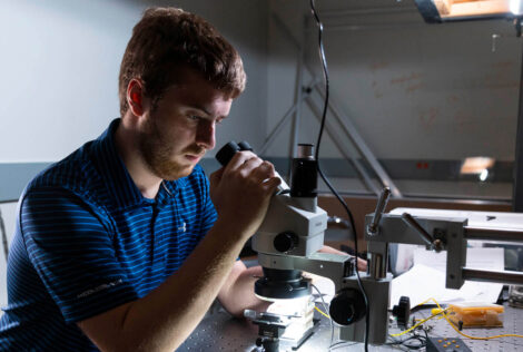 A person looks into a microscope in the Engineering Physics optics lab.