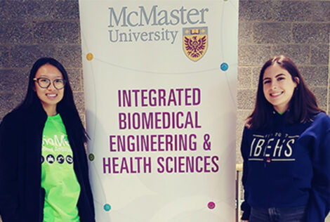 Two iBioMed ambassadors pose with a banner.