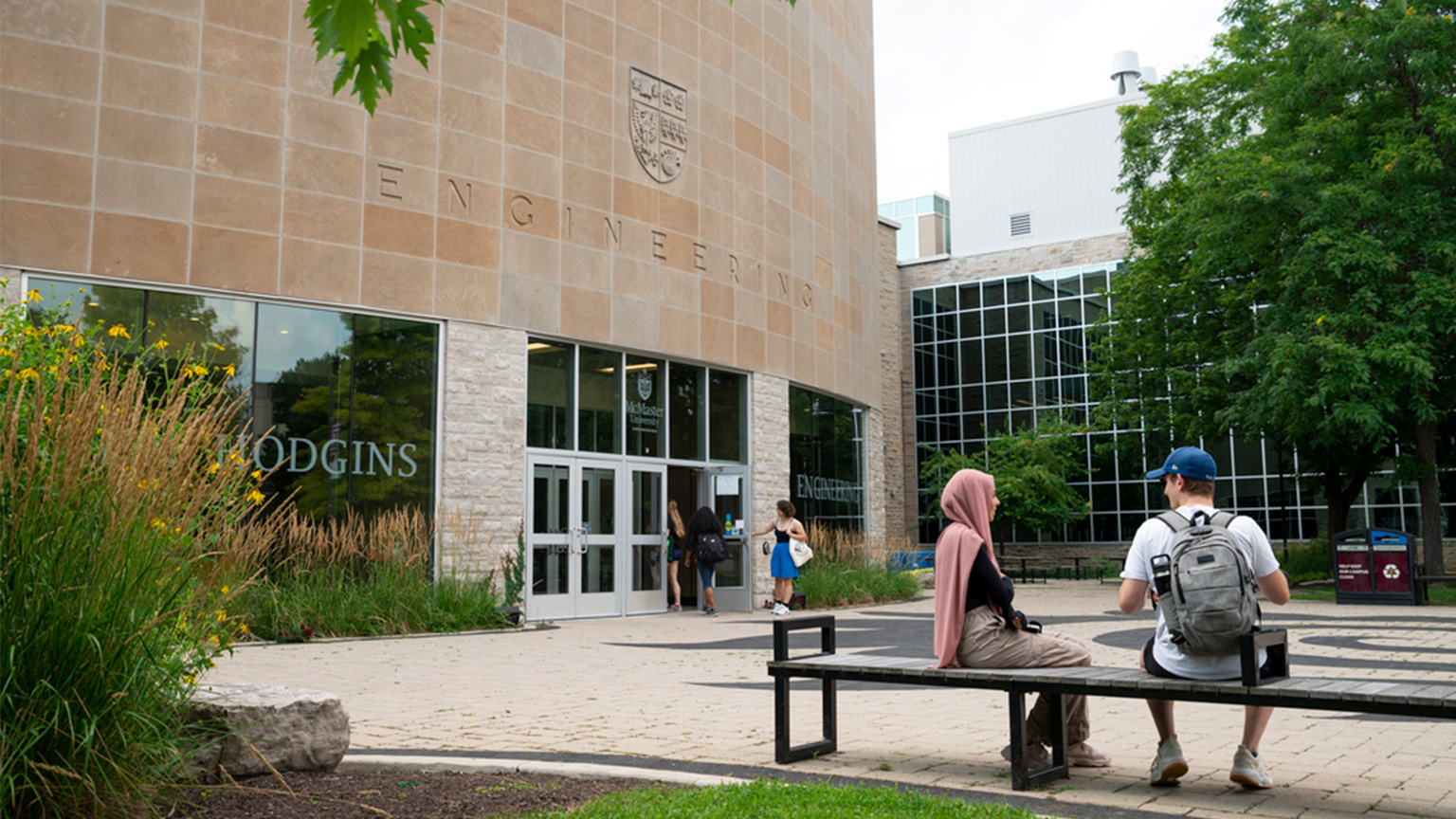 Students sit on a bench outside the John Hodgins Engineering Building entrance