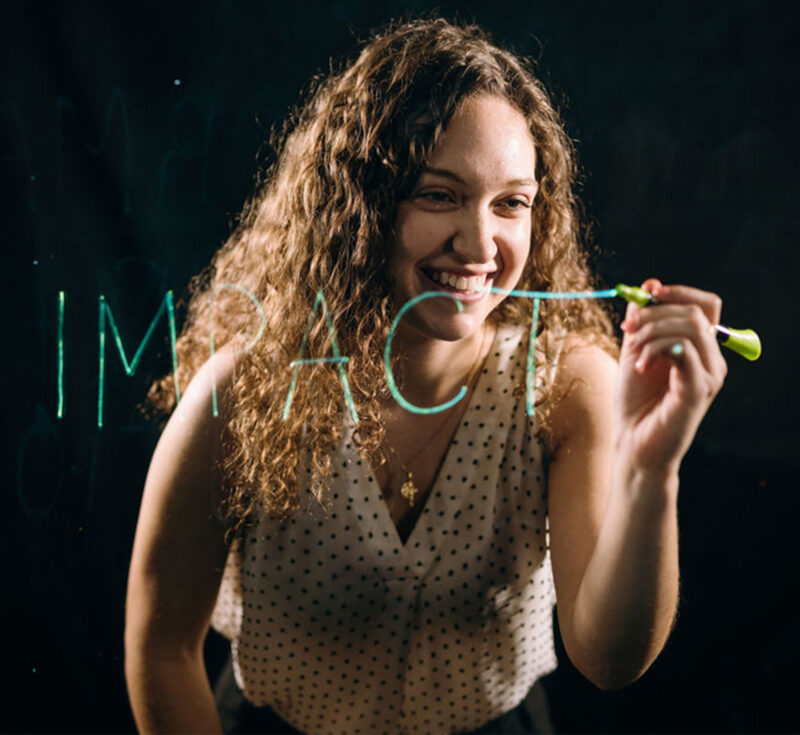 Lianna Genovese writes the word "impact" using a lightboard.