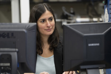 Woman sitting at a desk with two computer monitors facing her.