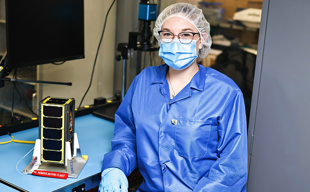 Magalie wearing PPE and posing with the NEUDOSE cube satellite