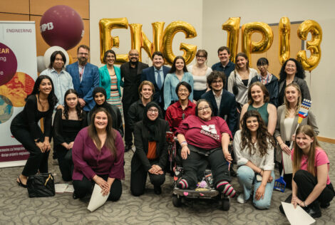 group picture of people posing in front of gold foil balloons.