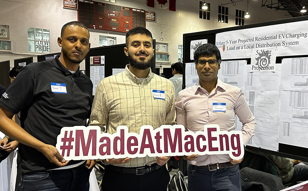 Three students pose with the hashtag Made at Mac Eng sign in front of their poster