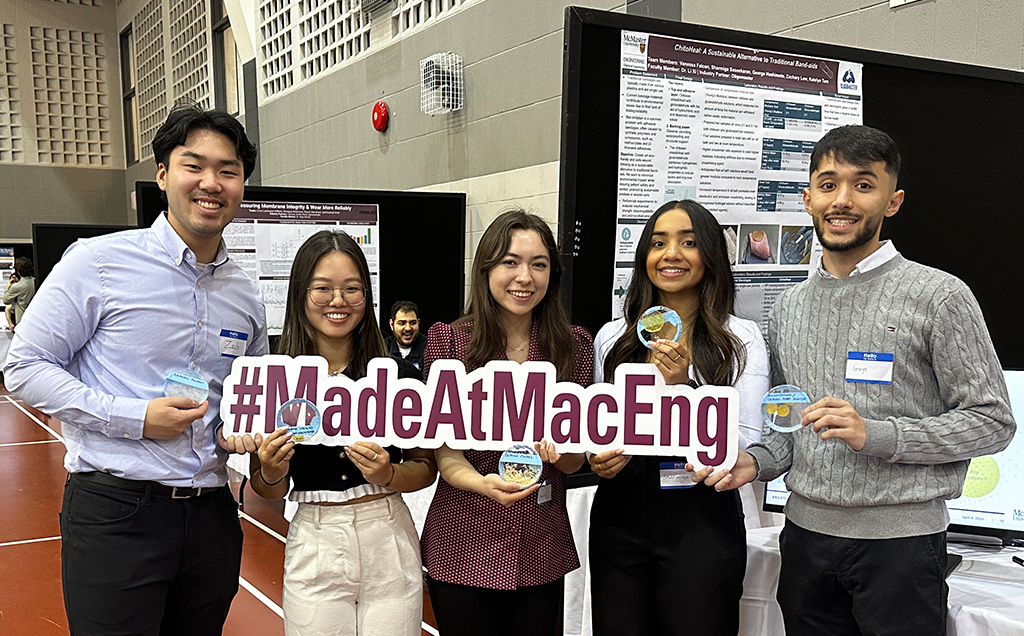 Five students pose with a #MadeAtMacEng sign in front of their Capstone Poster