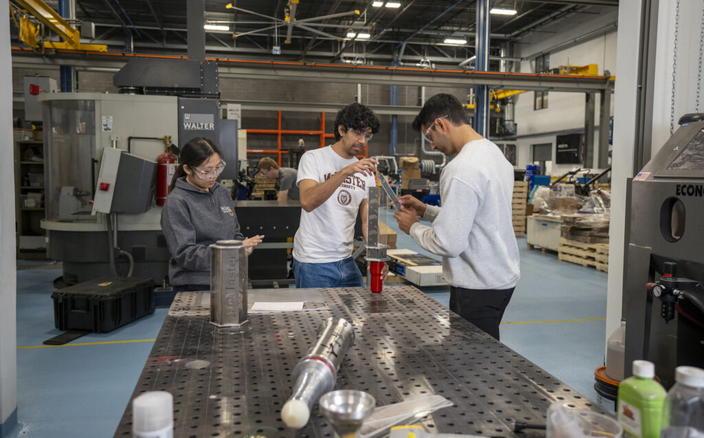 three students working together in a manufacturing warehouse.