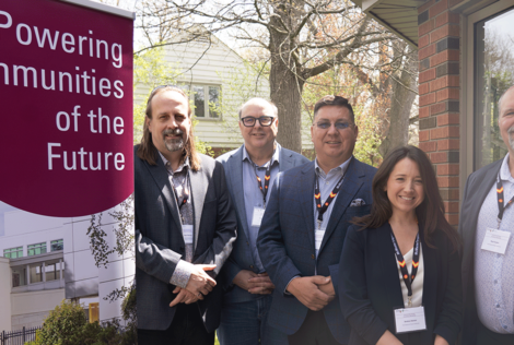 A group of people standing outside next to a Powering Communities of the Future sign