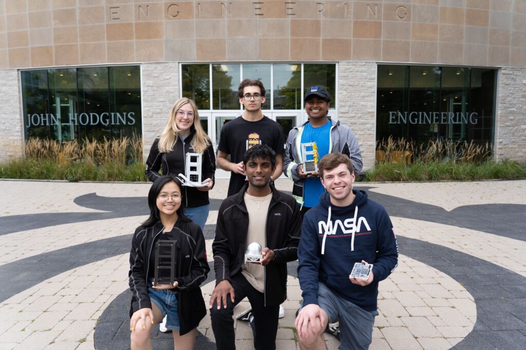 group of six students posing in front of an Engineering building on McMaster University's campus. 